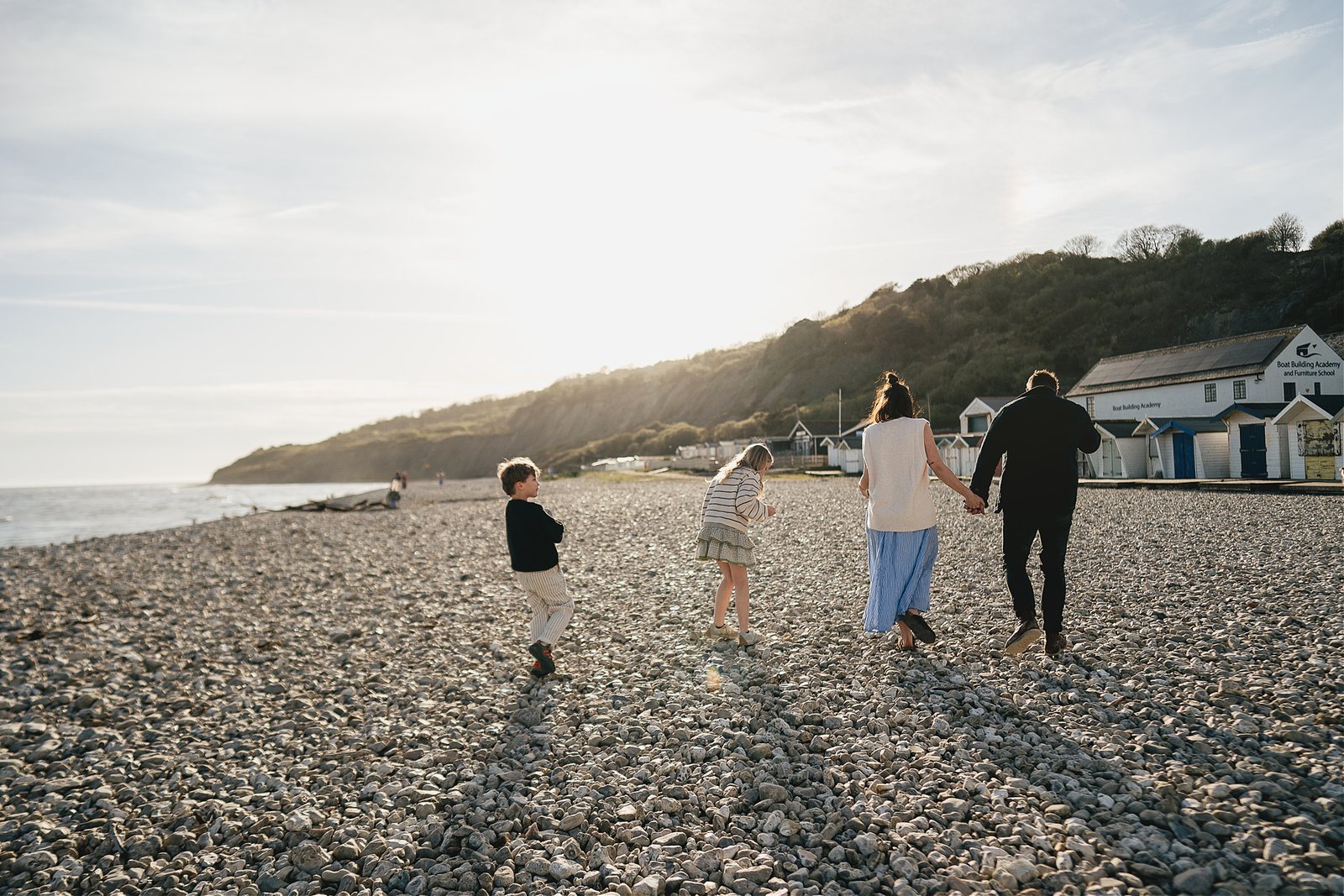 A family photography session in Lyme Regis, with a family walking across Monmouth beach