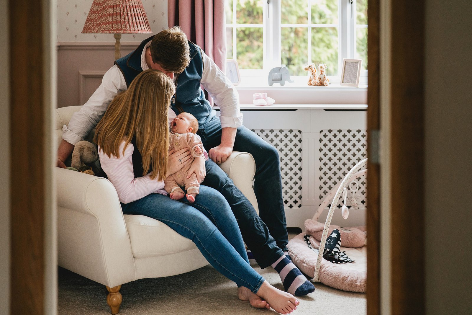 A couple with their newborn baby sitting together in the nursery during a baby photo session in Somerset