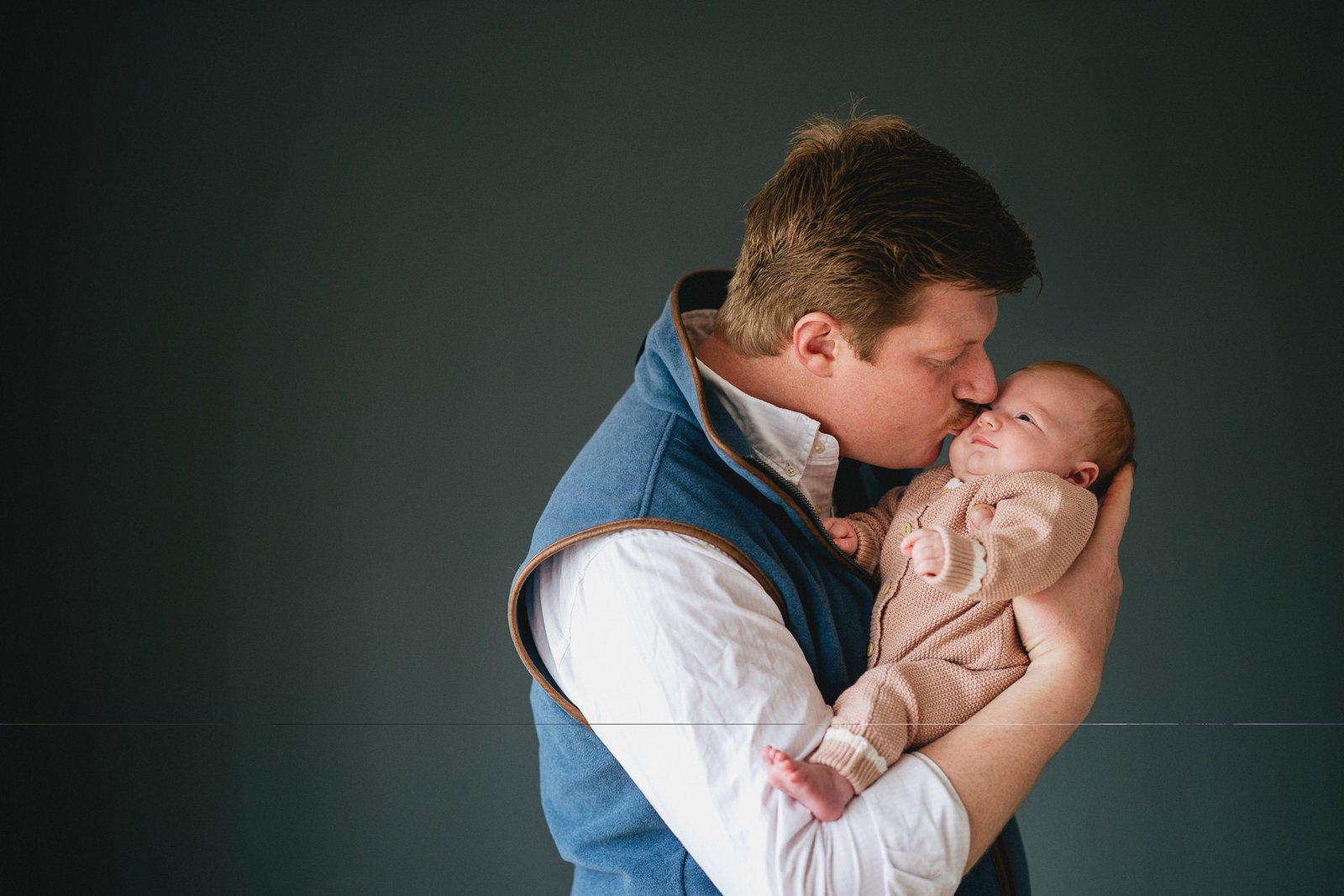 A father kissing a new baby at home in Somerset