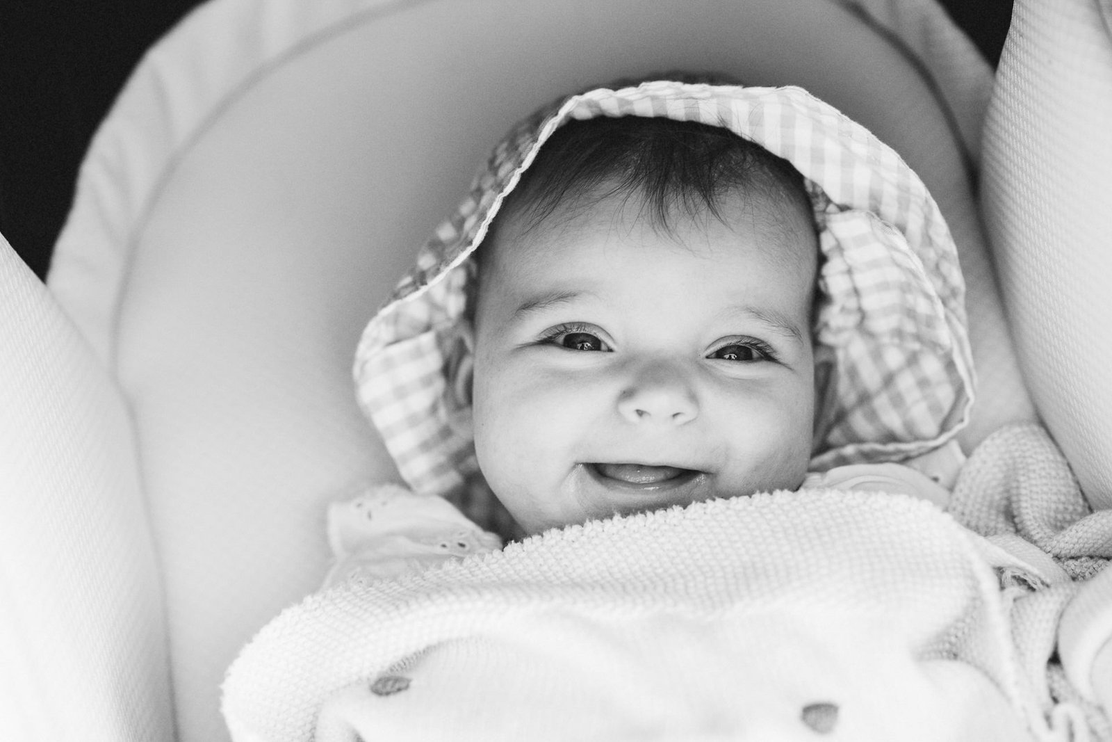 A baby smiling at the camera during a photography session by the beach in Devon