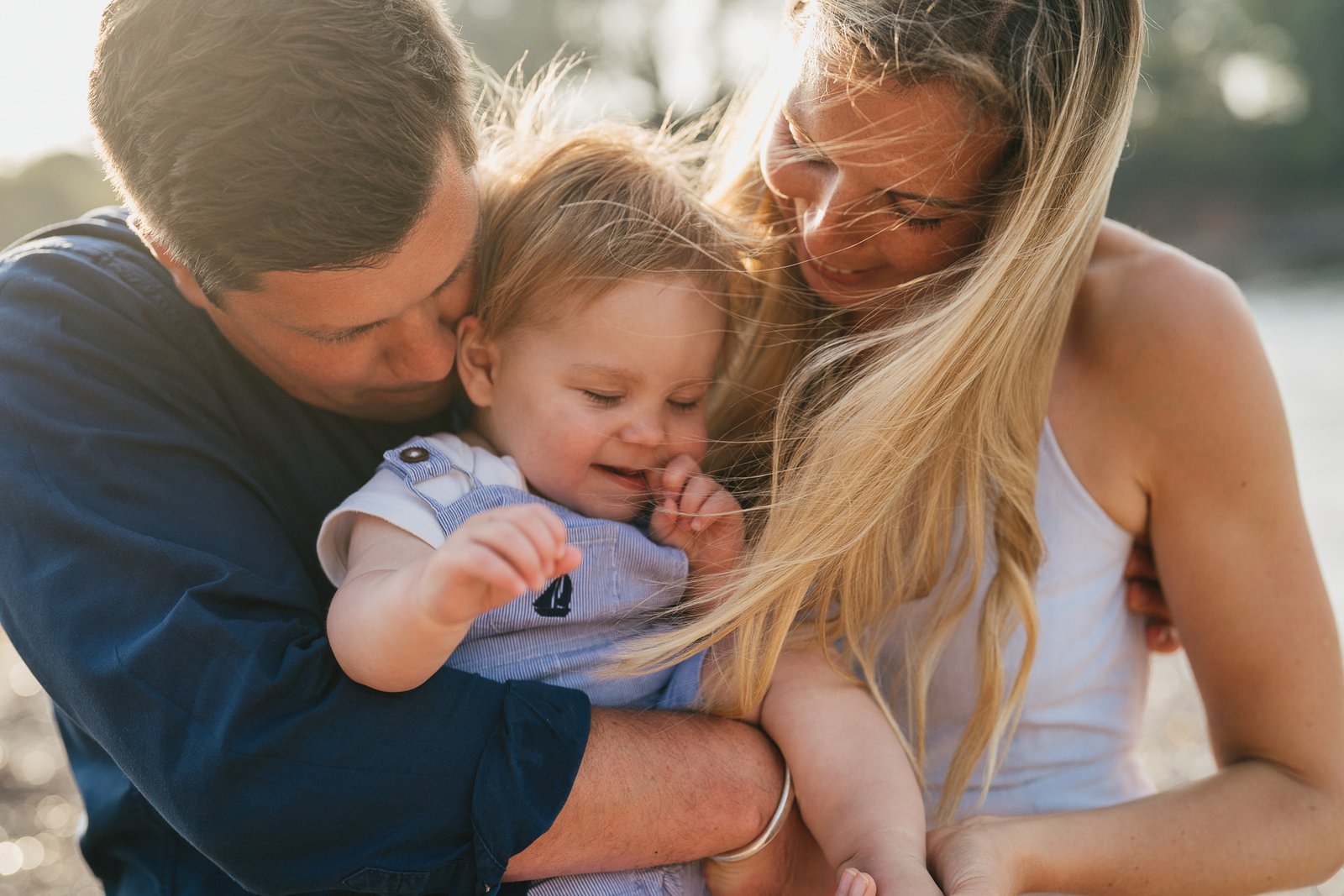 Parents cuddling with their baby son on the beach during a family photo session in Torbay