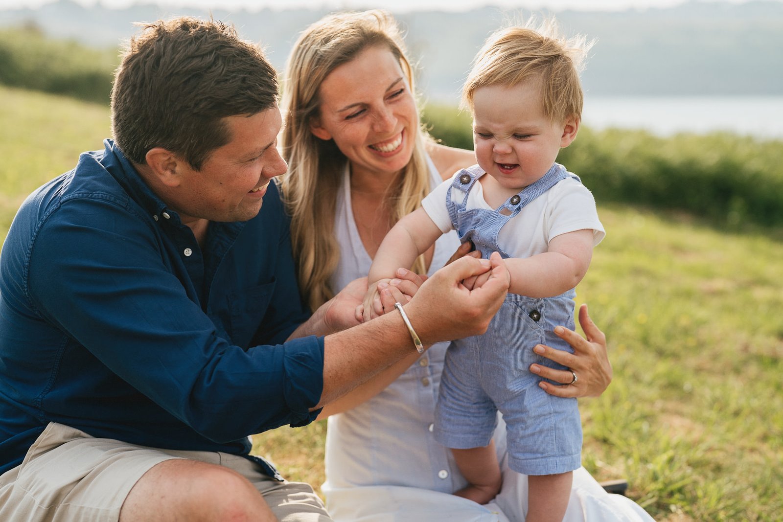 Parents cuddling with a toddler during a family photo session in Torbay